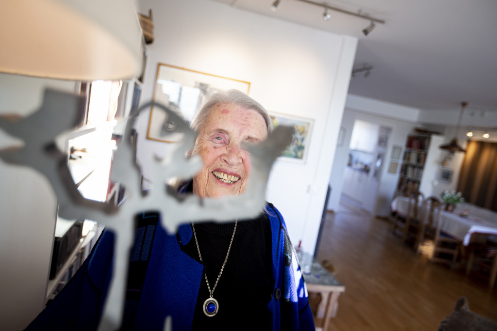 Smilende eldre dame i et oppholdsrom.